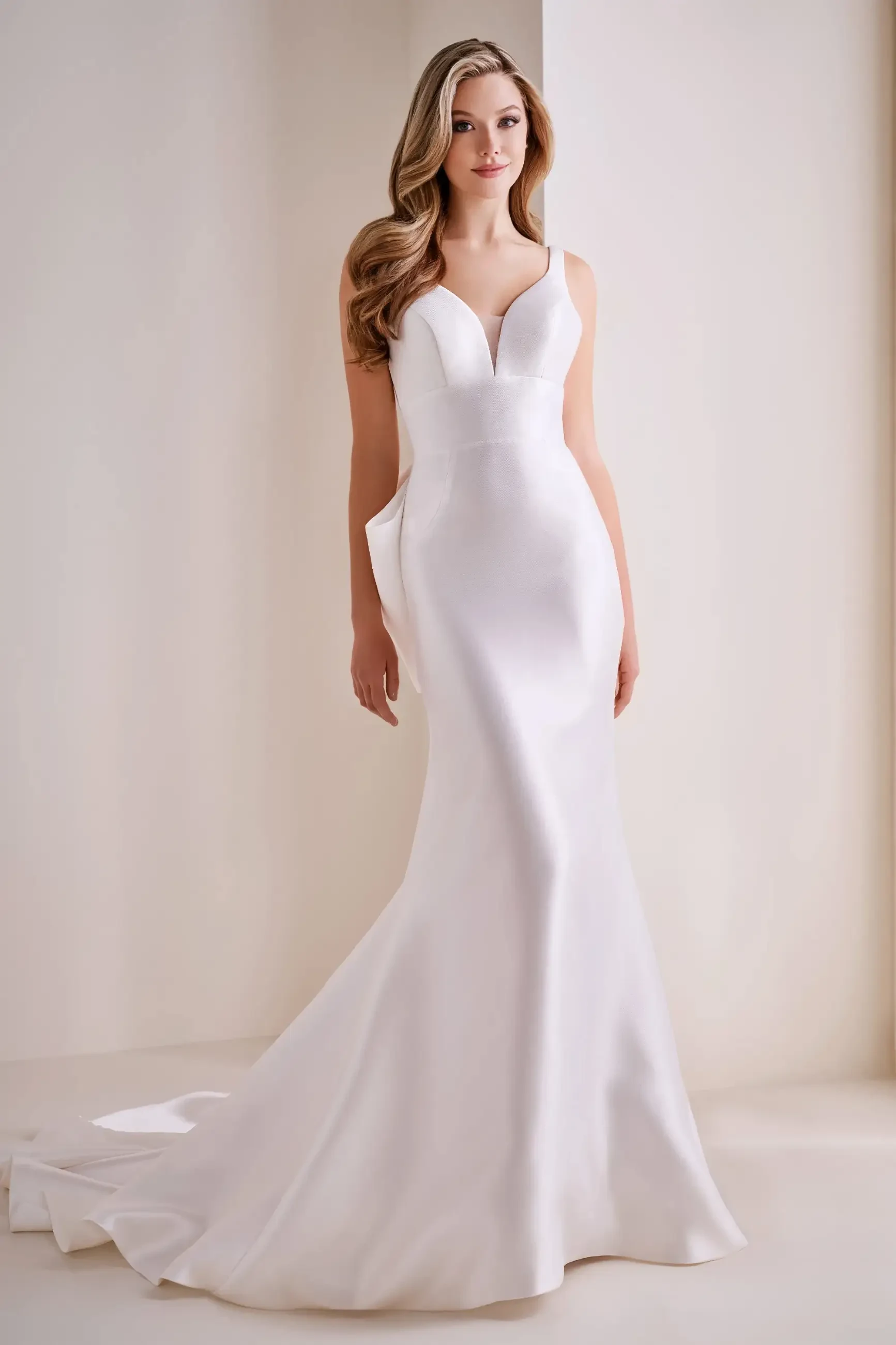 model is wearing a fit and flare sleeveless bridal gown with a bow on the back
